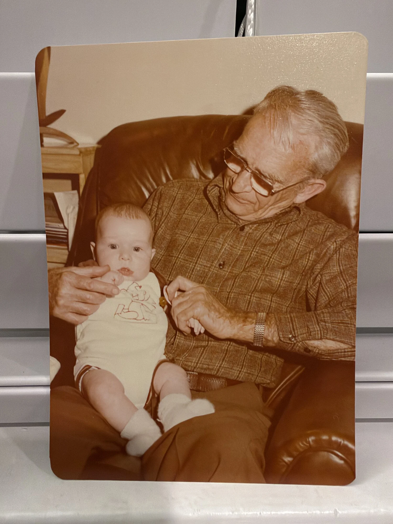 Baby Mike on Grandpa Jack's lap in a leather armchair