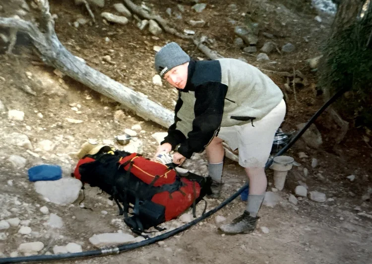 Mike as a young scout packing a red backpack at Philmont