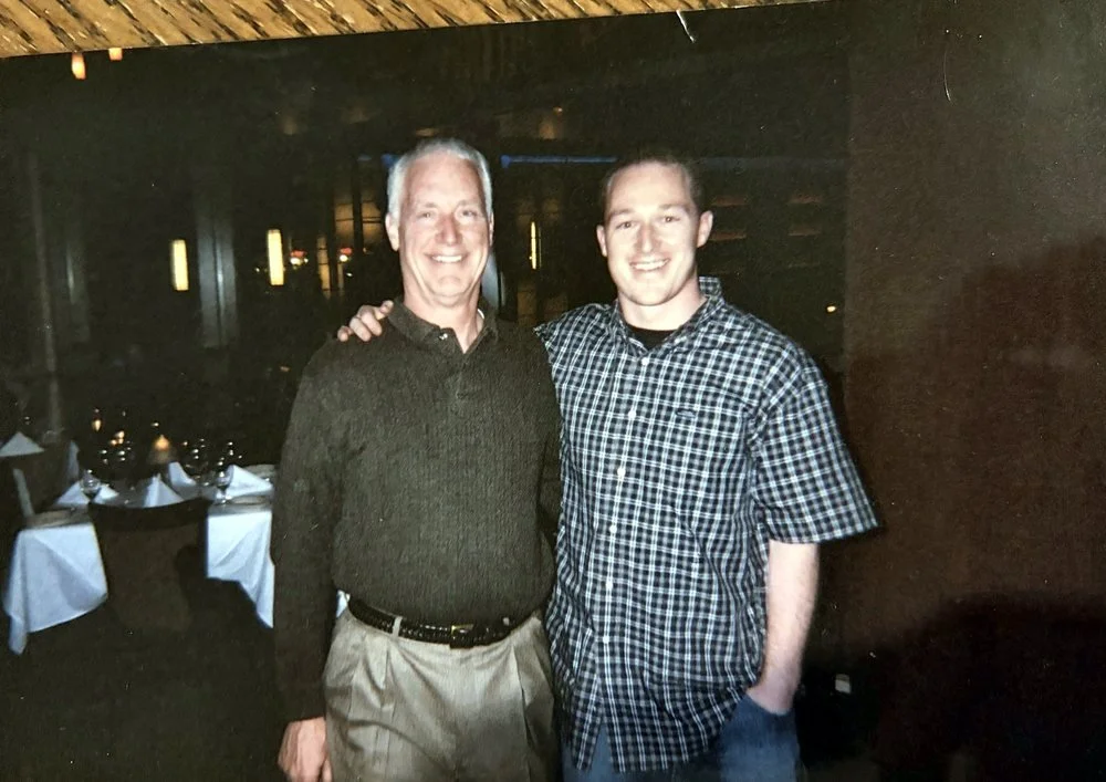 Mike and his dad smiling together at a restaurant on Mike's college graduation night