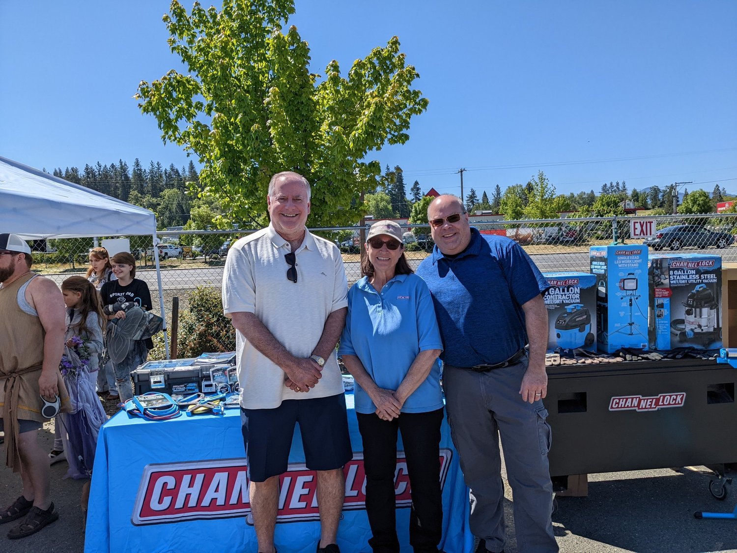 Three people beside a Channellock product display at an outdoor member event