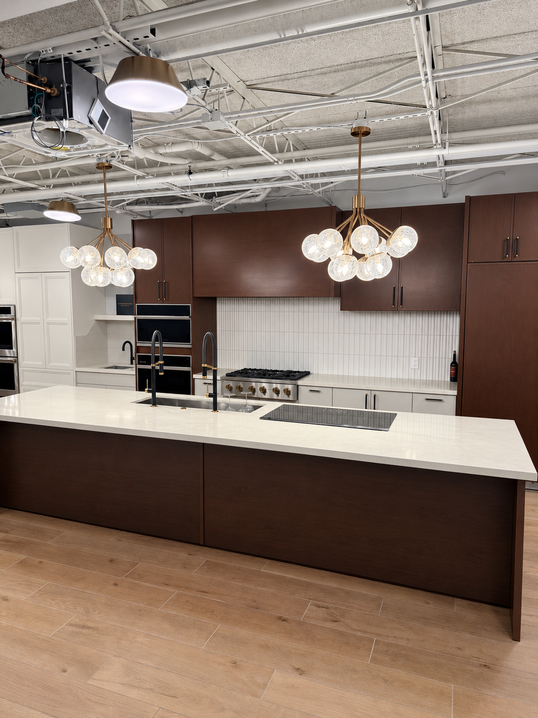 Rich wood cabinetry, a ribbed white backsplash and dual black island faucets in the TLTH showroom.