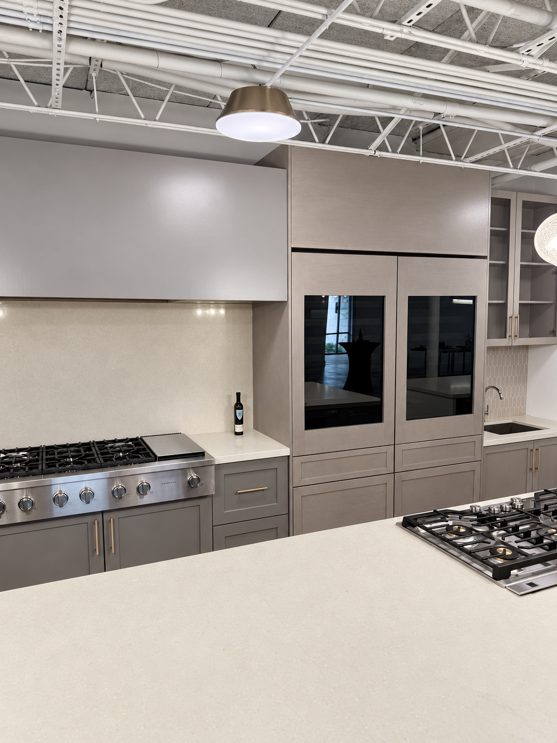 Taupe cabinetry with integrated refrigeration, a gas range and island cooktop at The Luxury Tree House.