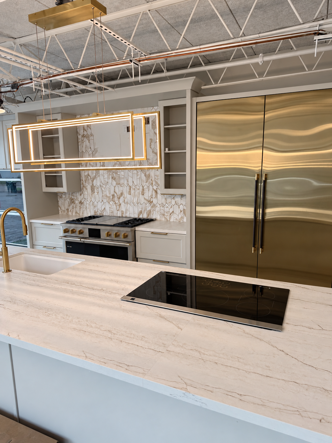 Brass refrigeration panels, patterned backsplash and a veined island countertop in the TLTH showroom.