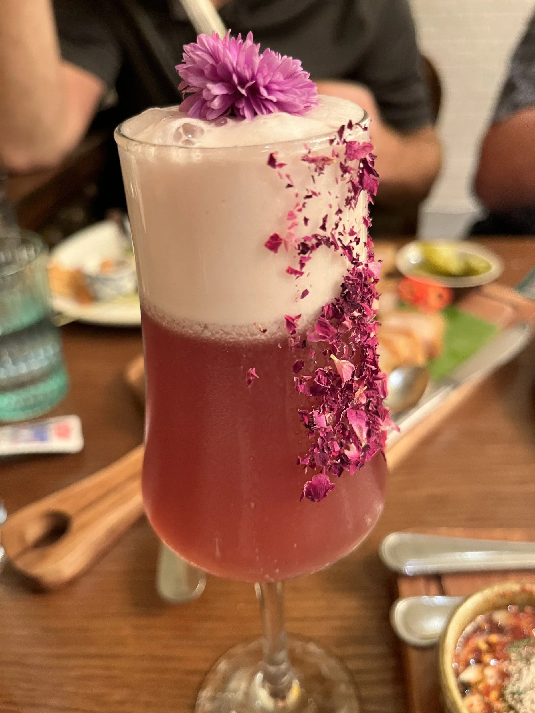 A pink cocktail topped with an orchid