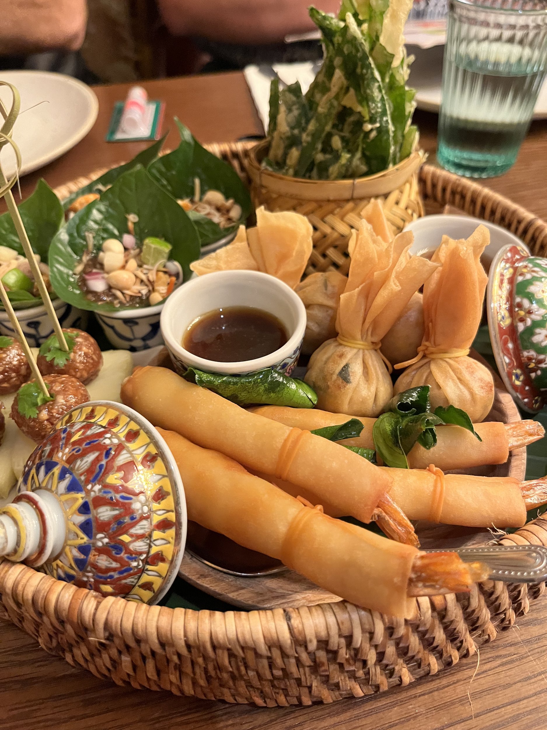 A Thai appetizer platter with spring rolls, golden money bags and dipping sauce