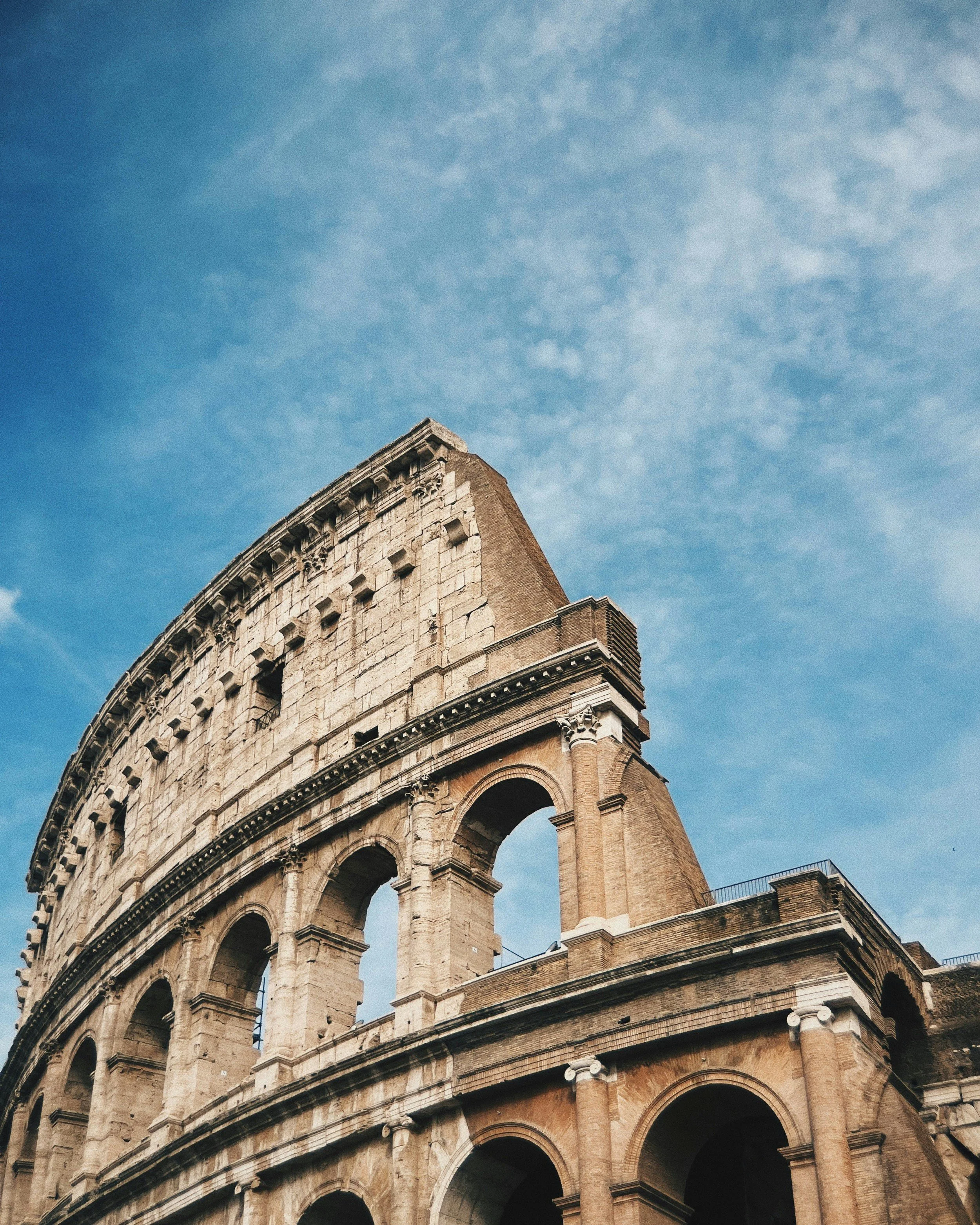 The arches of the Colosseum in Rome against a blue sky