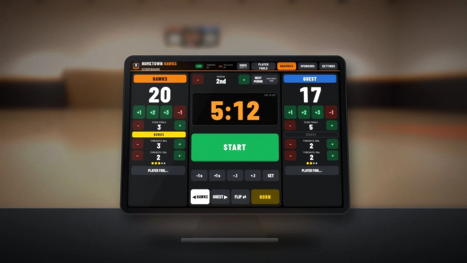 Concept rendering of the touchscreen scoreboard console on a stand at a gym scorer’s table, showing HAWKS 20 GUEST 17, a 5:12 game clock and a big START button