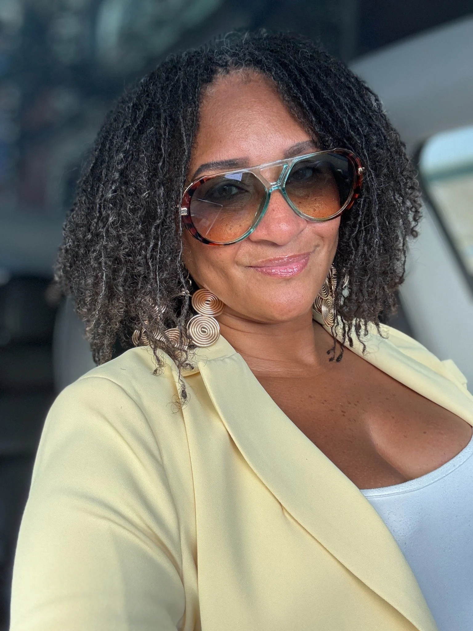 Nisha wearing sunglasses and a pale yellow jacket