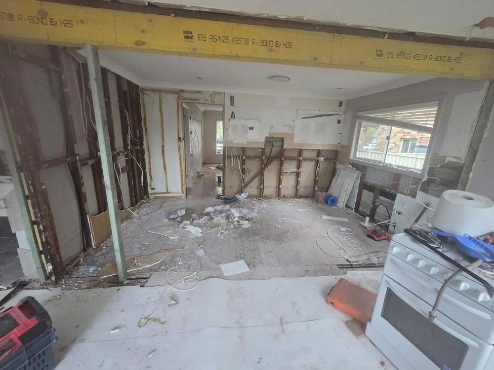 Before: wall framing exposed and old kitchen stripped out under a new beam
