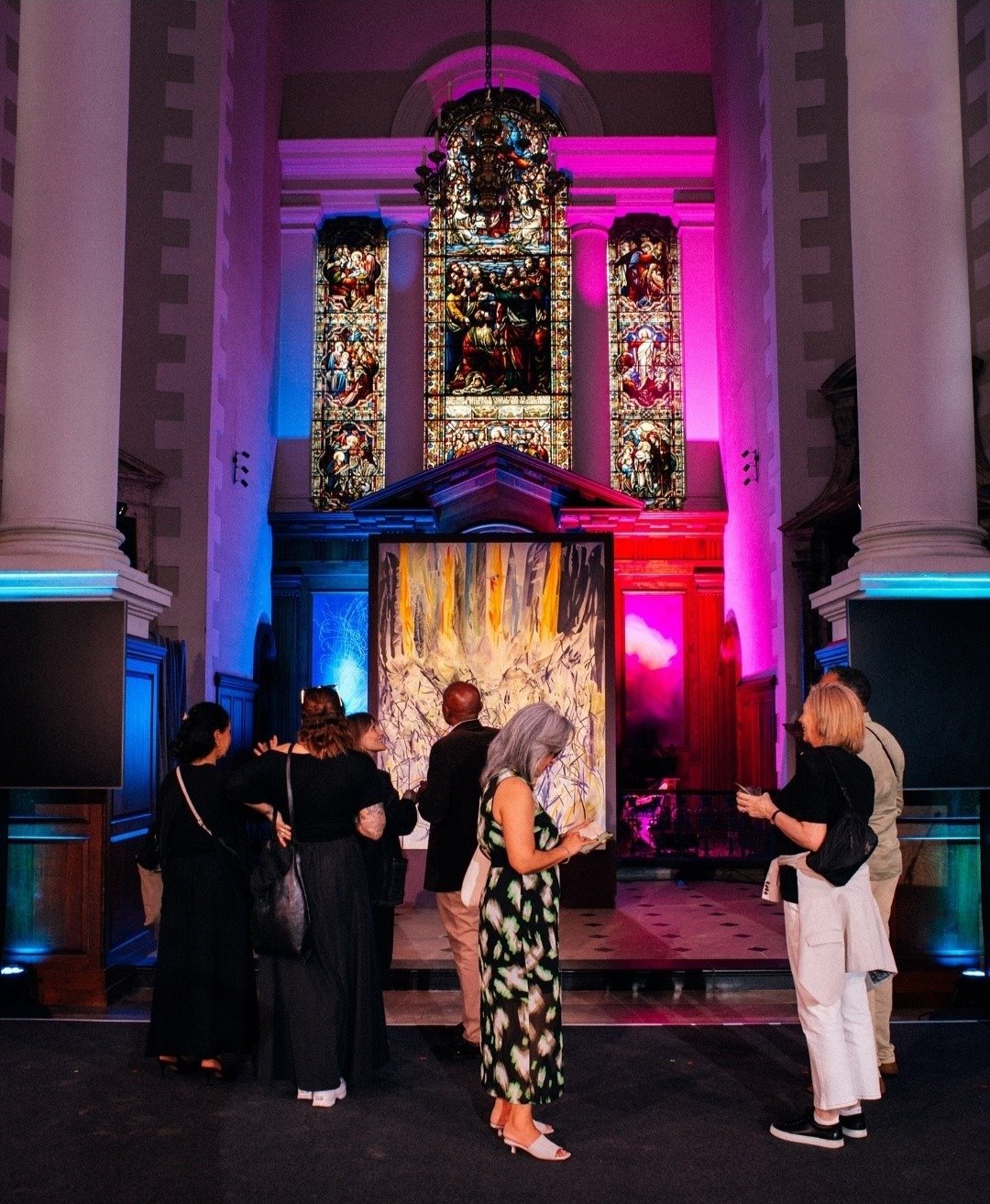 Guests exploring an artwork installation in the Nave under colourful lighting