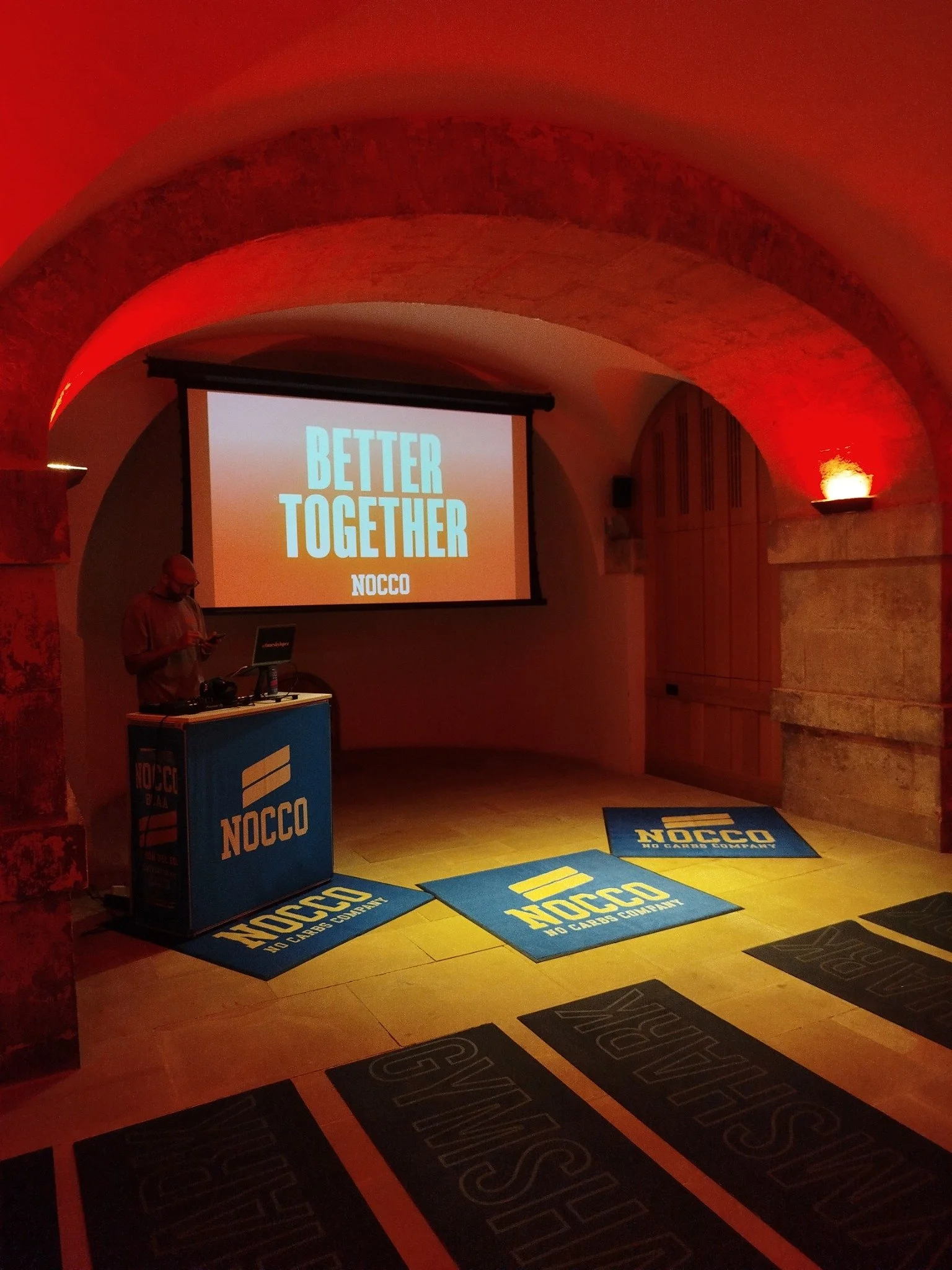 A NOCCO brand setup with screen and branded floor mats beneath the Crypt’s stone arches