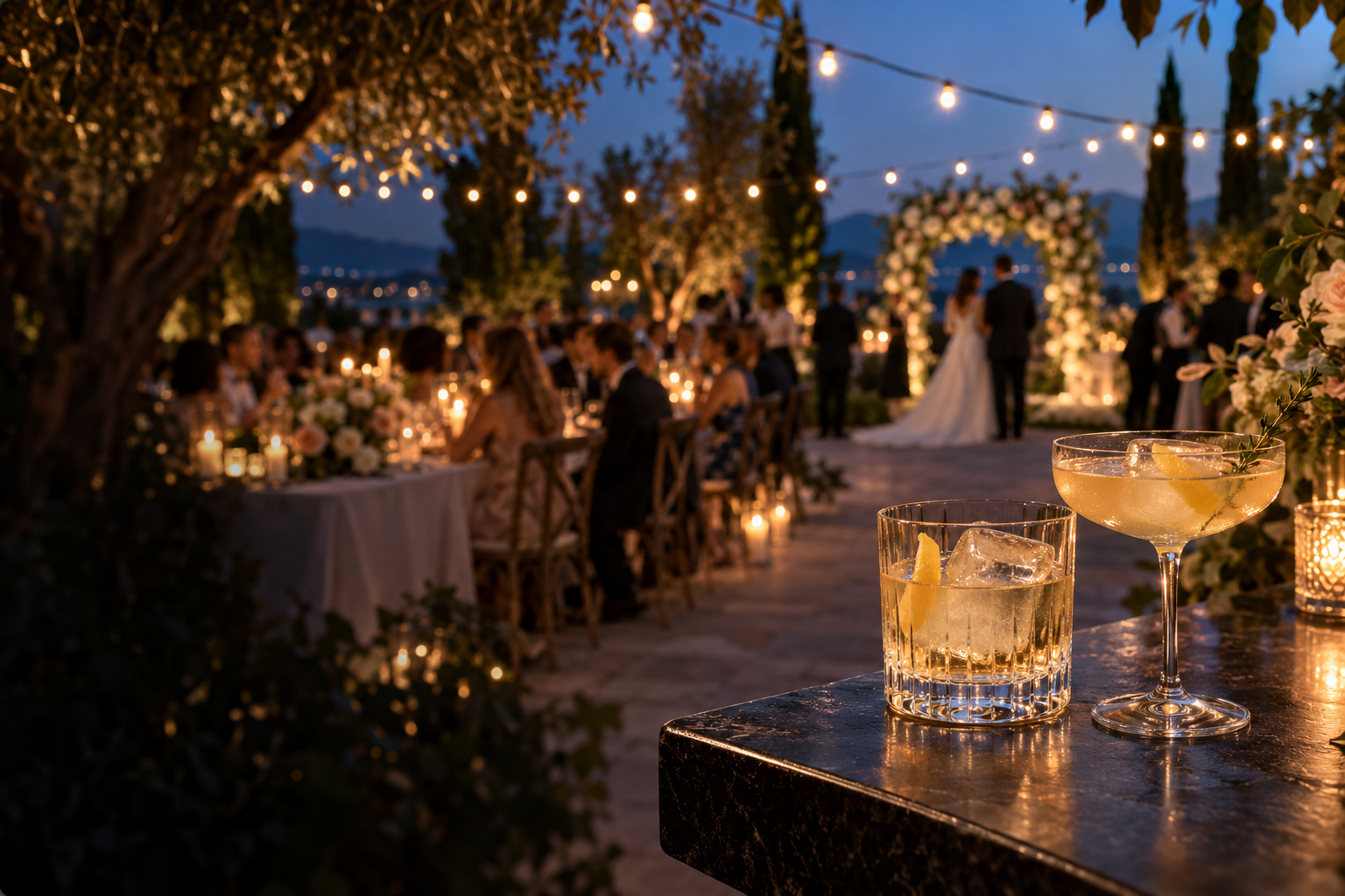 Clear ice cocktails at a garden wedding, with the couple and floral arch in the background