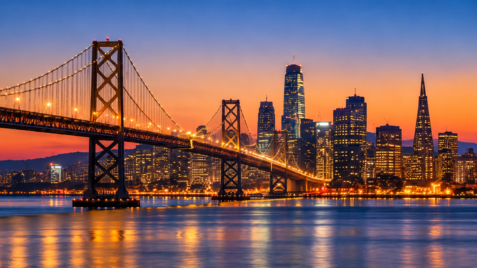 Bay Bridge and the San Francisco skyline glowing at twilight