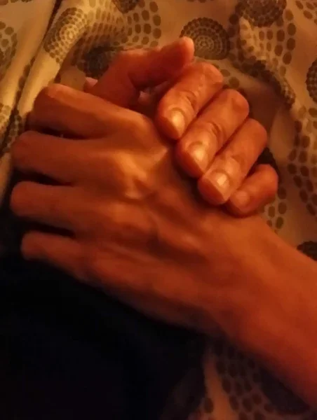 Close-up of two hands clasped together.