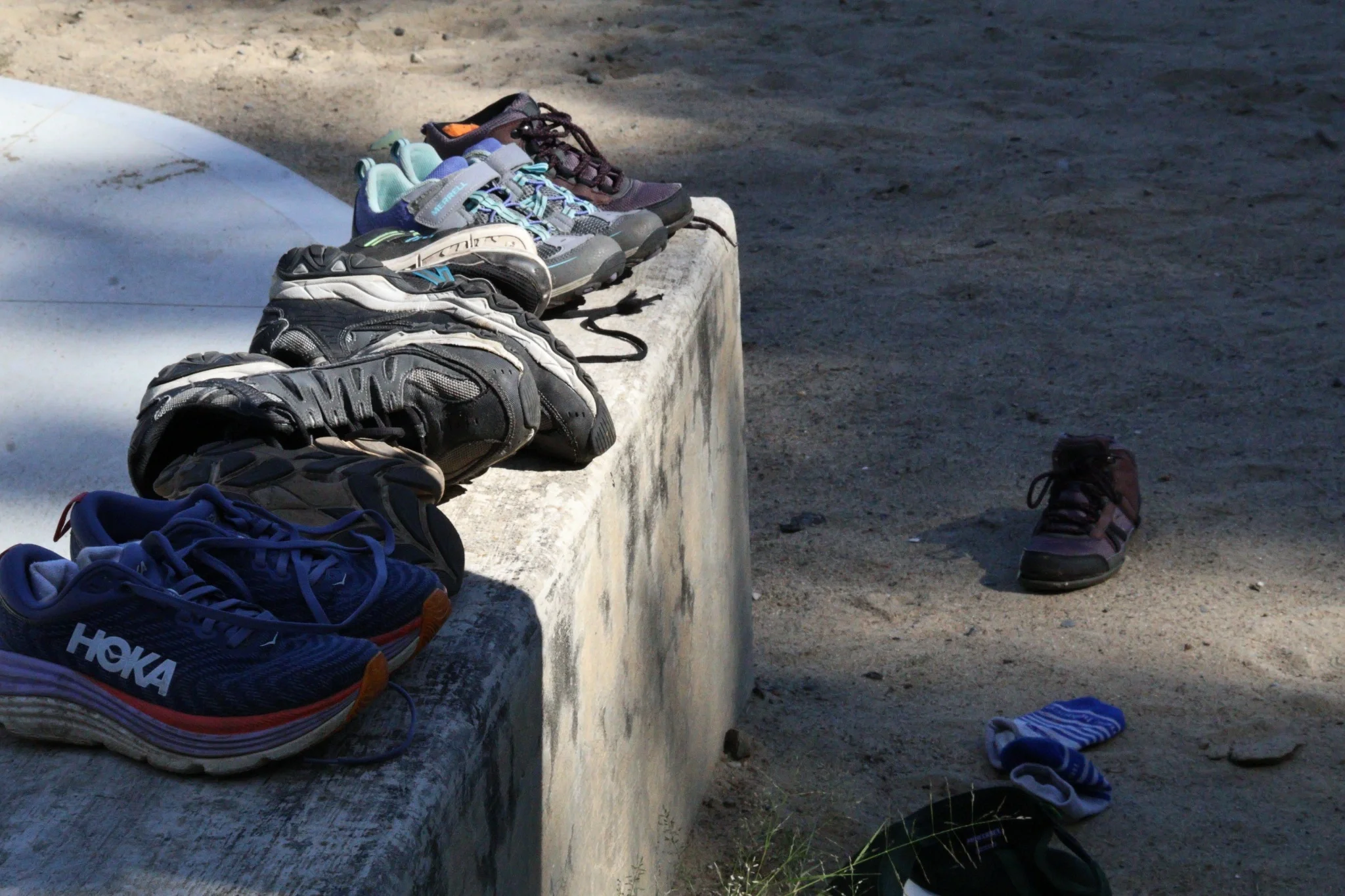 Lost shoes collected and lined up on outdoor steps near a state park beach, waiting to be claimed.