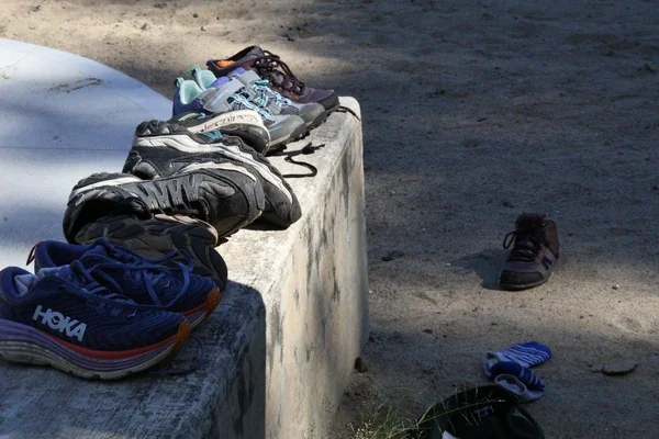 Lost shoes collected and lined up on outdoor steps near a state park beach, waiting to be claimed.