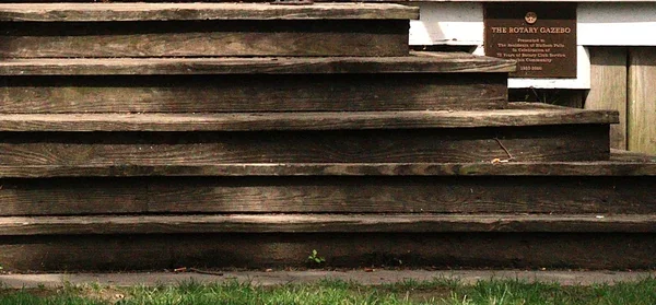 Old weathered wooden steps leading into the Rotary Gazebo, with its plaque visible beside the entrance.