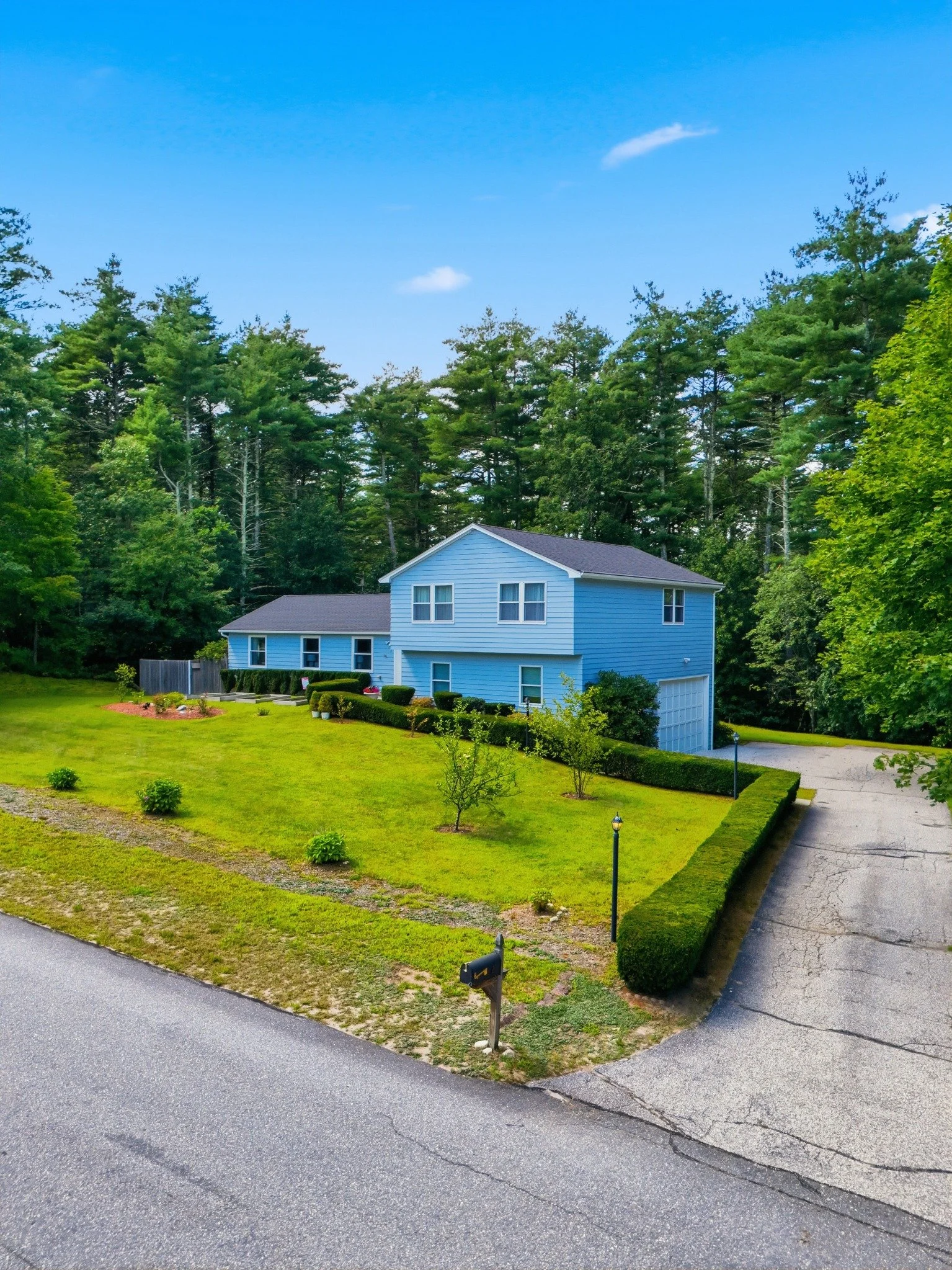 Blue home surrounded by trees at 7 Twin Street in Windham, New Hampshire