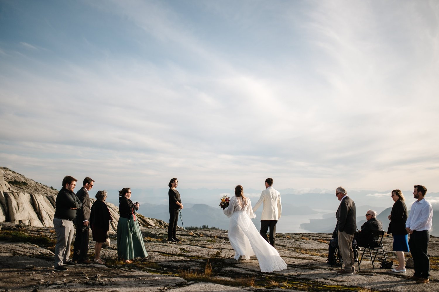 Guests watching a couple exchange vows on a mountaintop