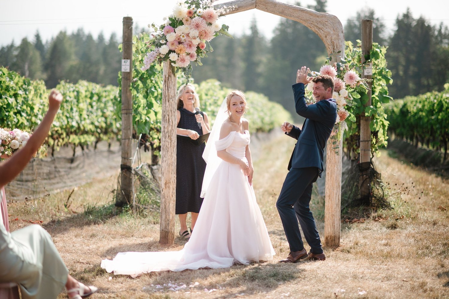 Charlie and Myles beneath the floral arch in the vineyard