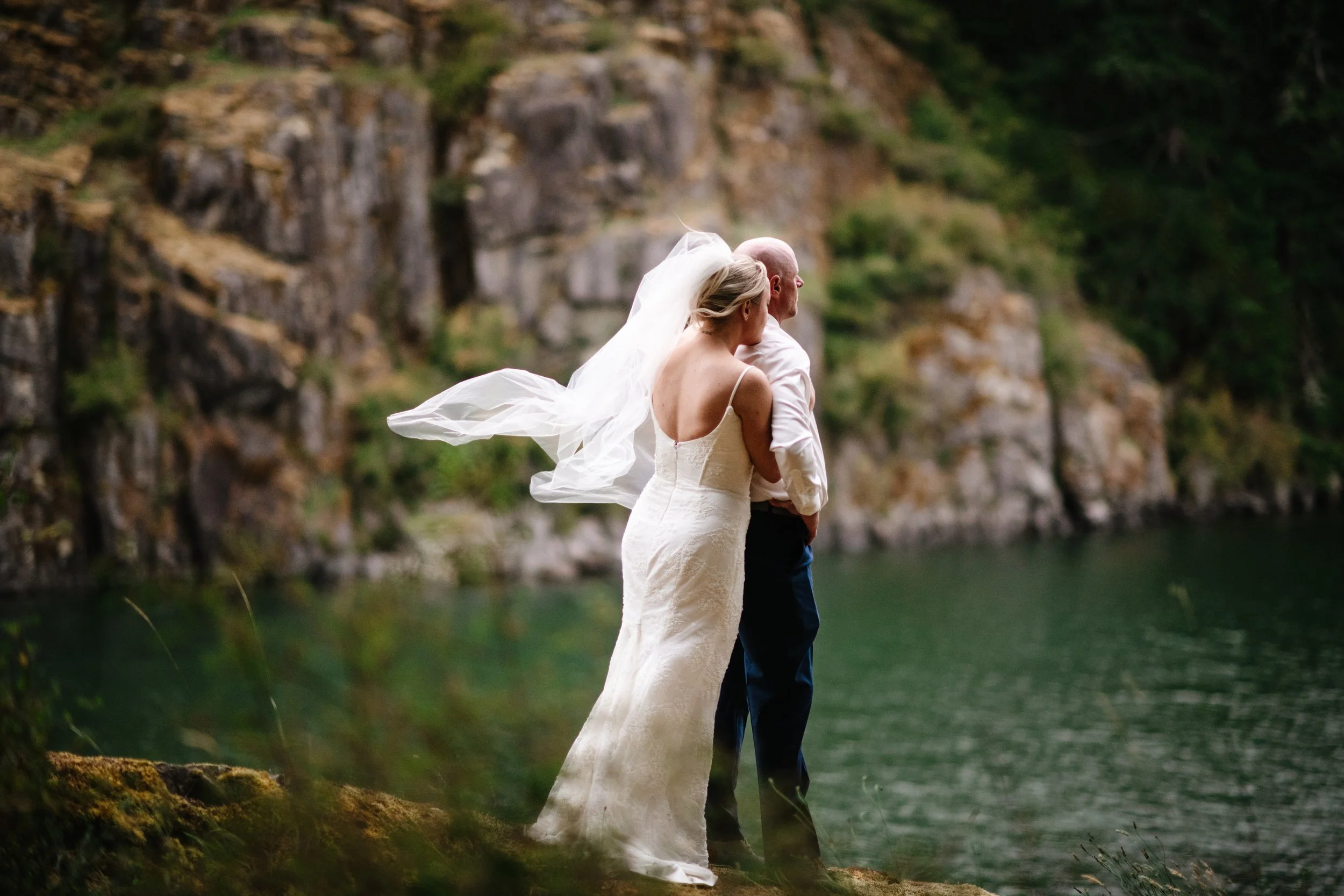 Hailey and Kyle sharing a kiss beside the rocks at the water’s edge