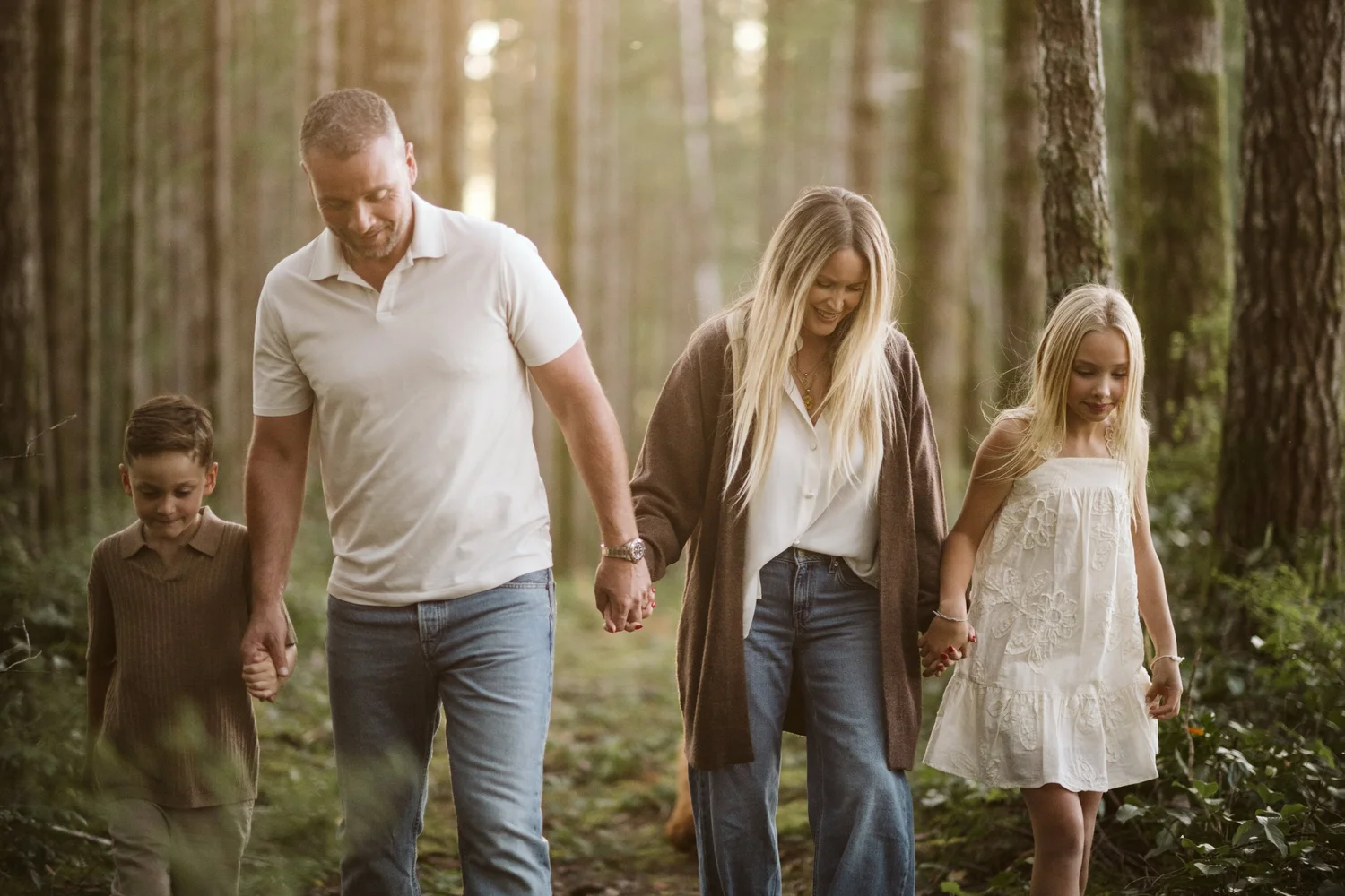A family walking hand in hand through a sunlit forest