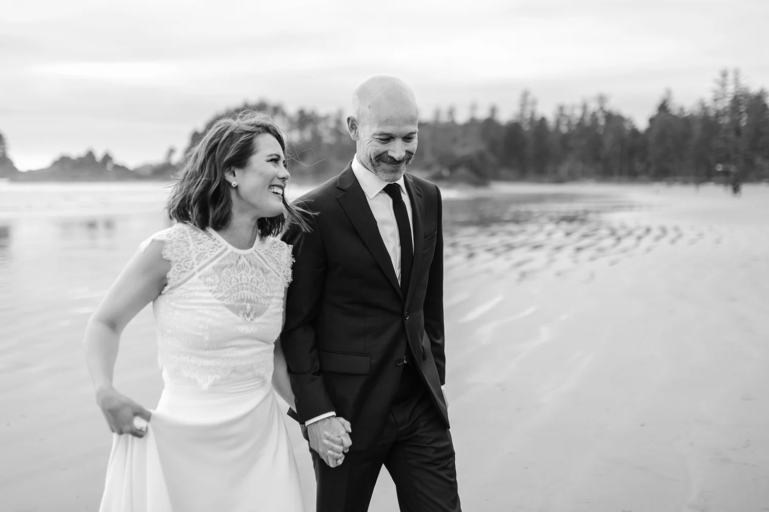 Sarah and Philip walking hand in hand on the beach in Tofino