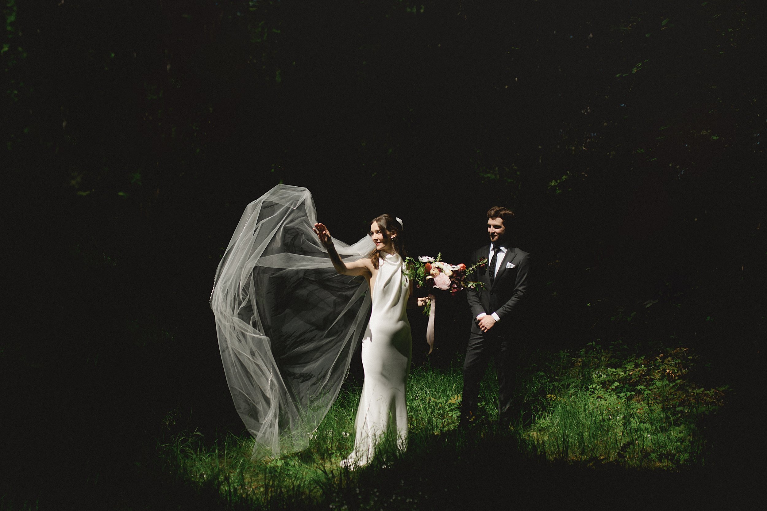 Dana’s veil catching the wind as she walks with Cole in the dark woods