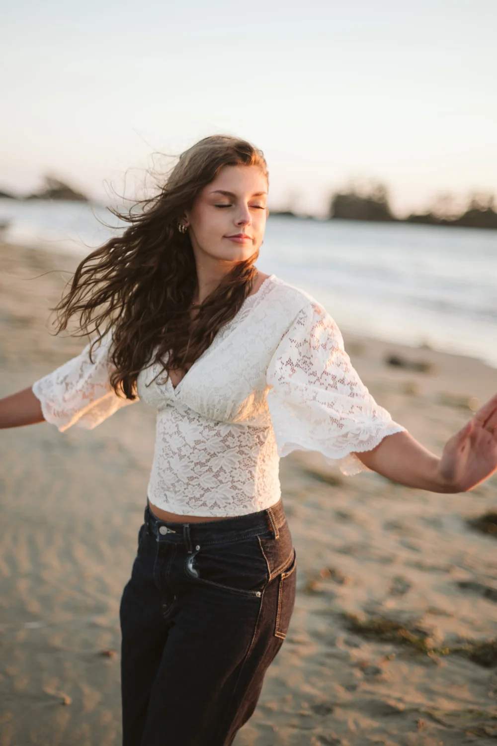 A young woman in white lace on the beach, hair in the wind