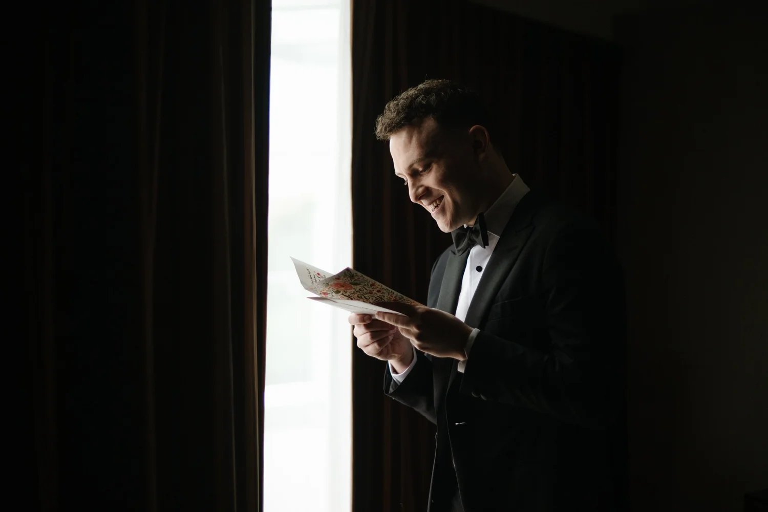 The groom reading a letter by the window