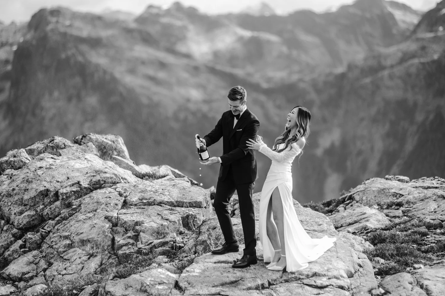 A couple celebrating on a mountaintop, in black and white