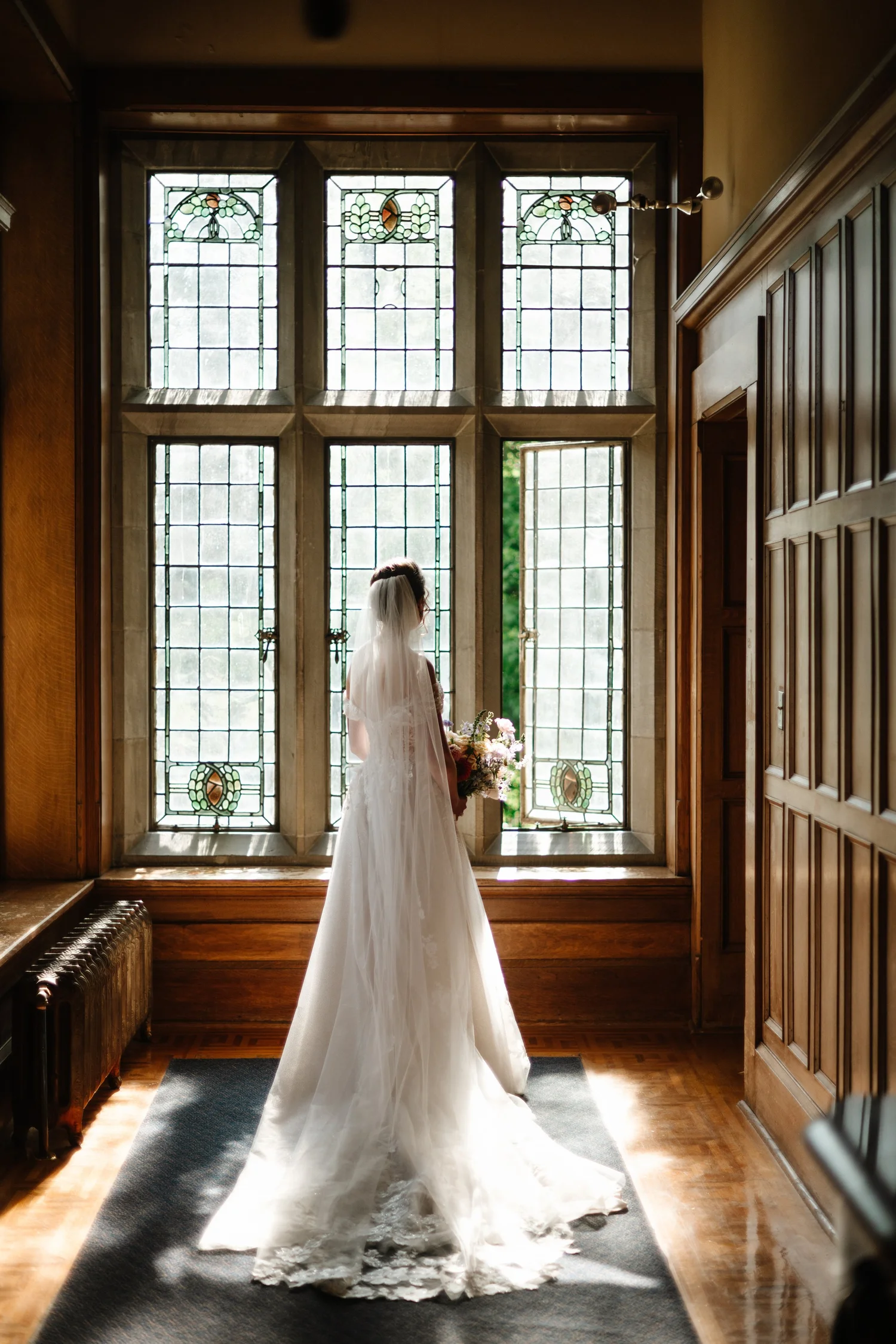 The bride in her gown by tall castle windows