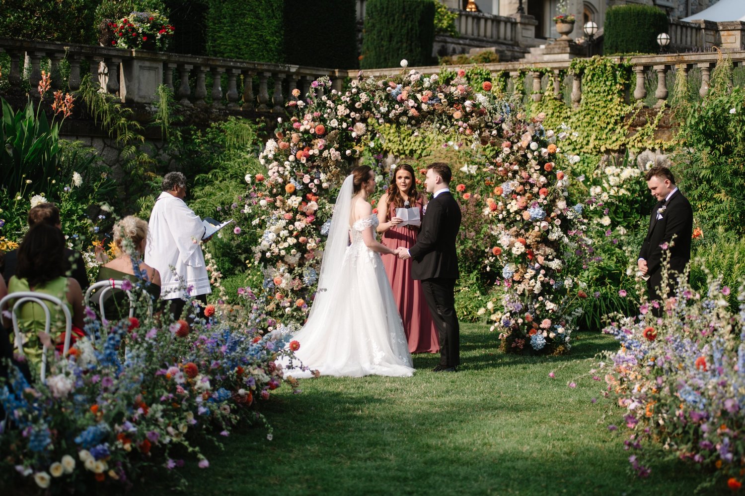 The ceremony under a floral arch in the gardens