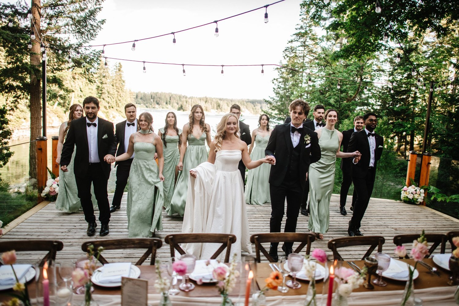 The wedding party arriving on the deck under string lights