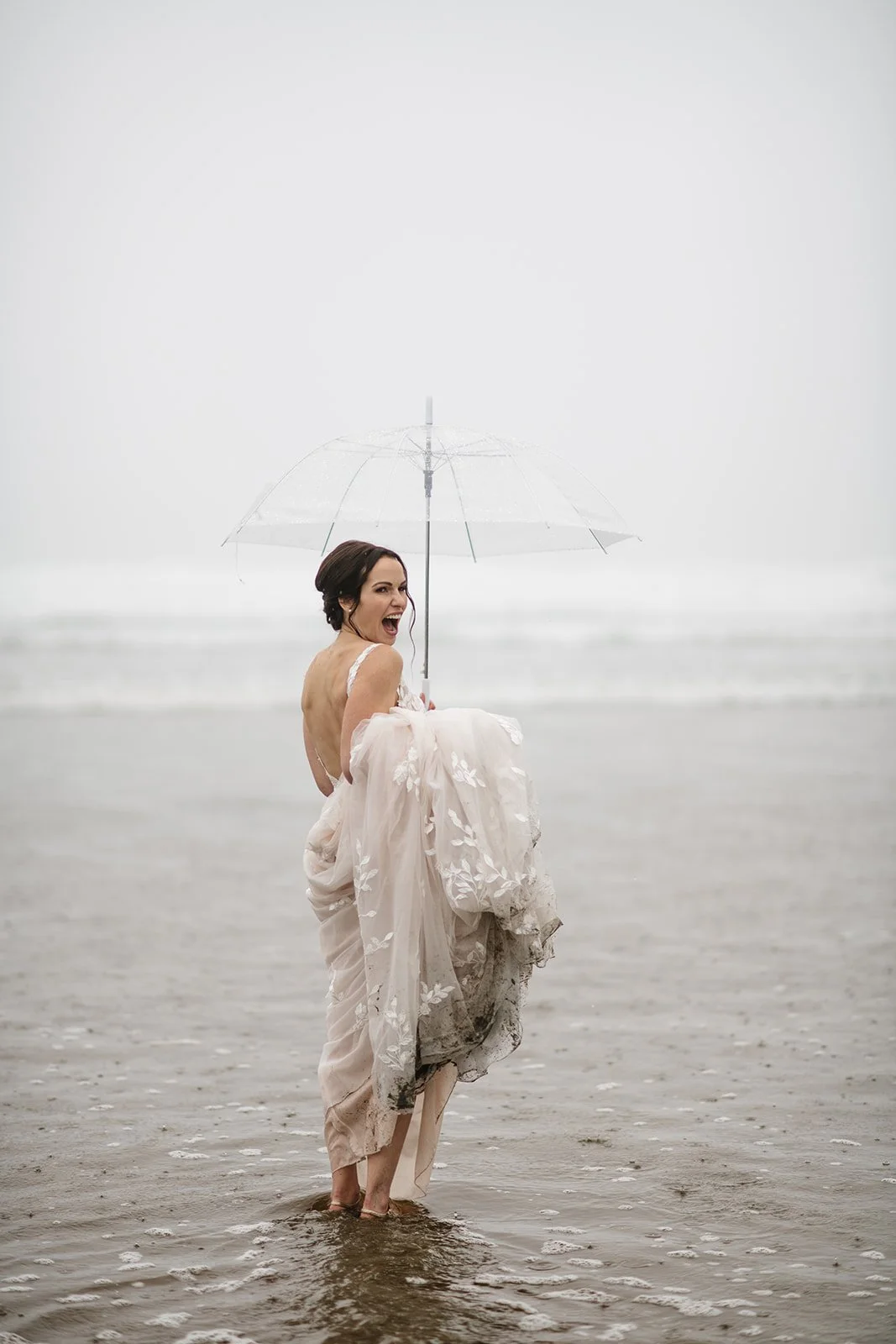 A bride with a clear umbrella standing in the sea