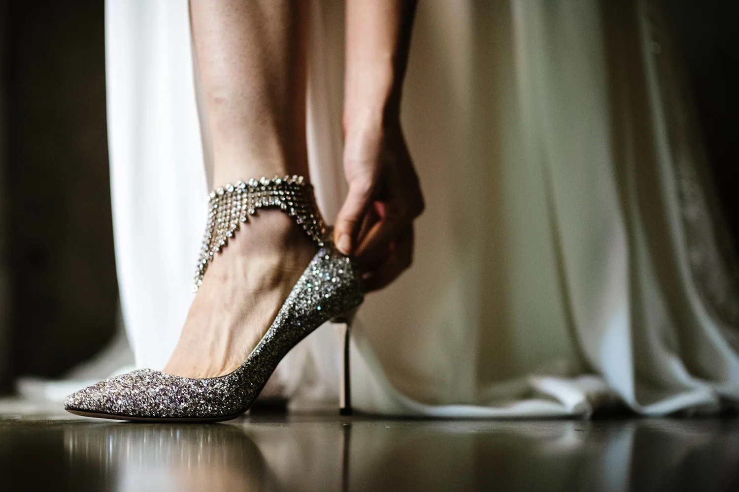 A bride fastening her sparkling heels while getting ready