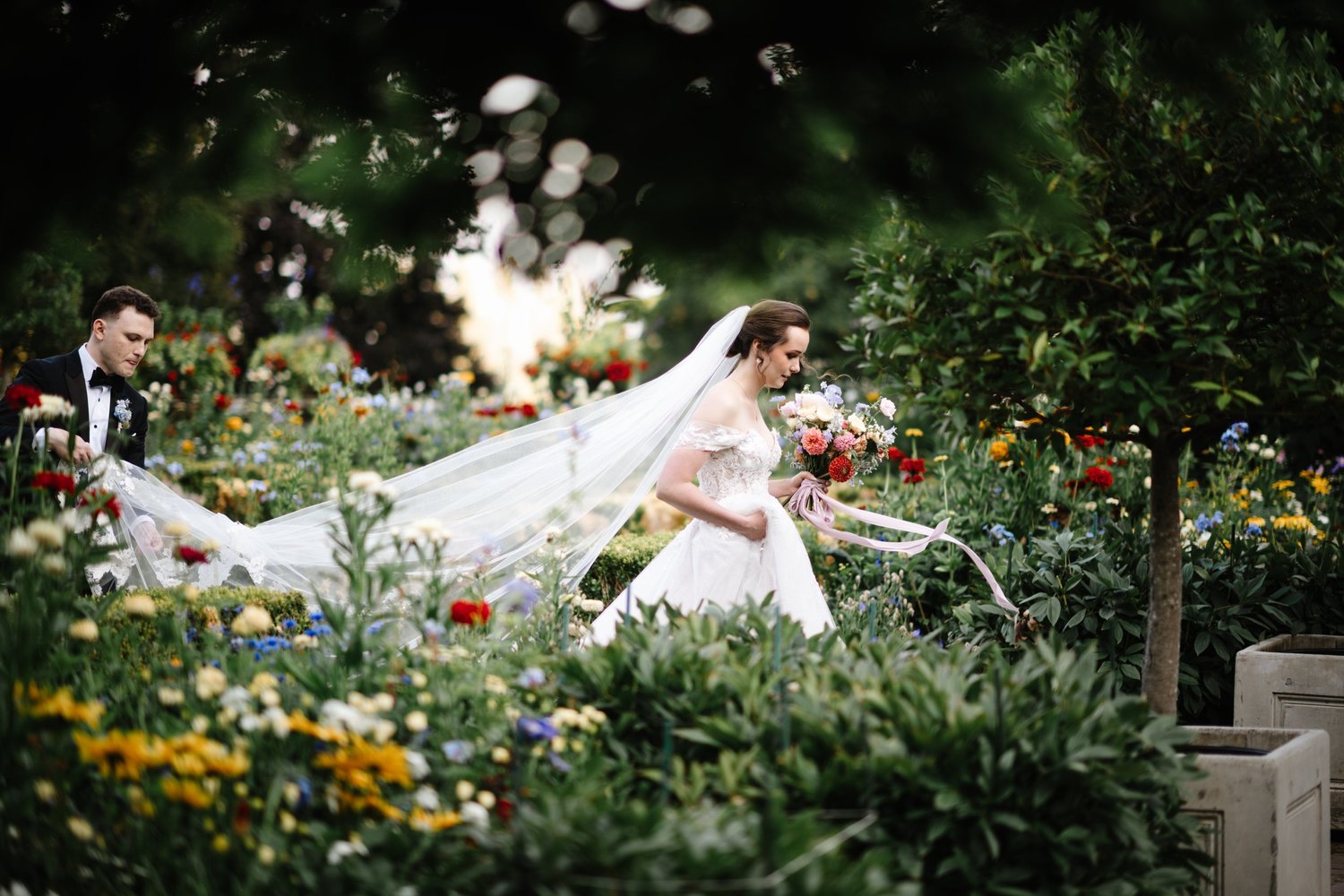 The bride under her veil in the gardens