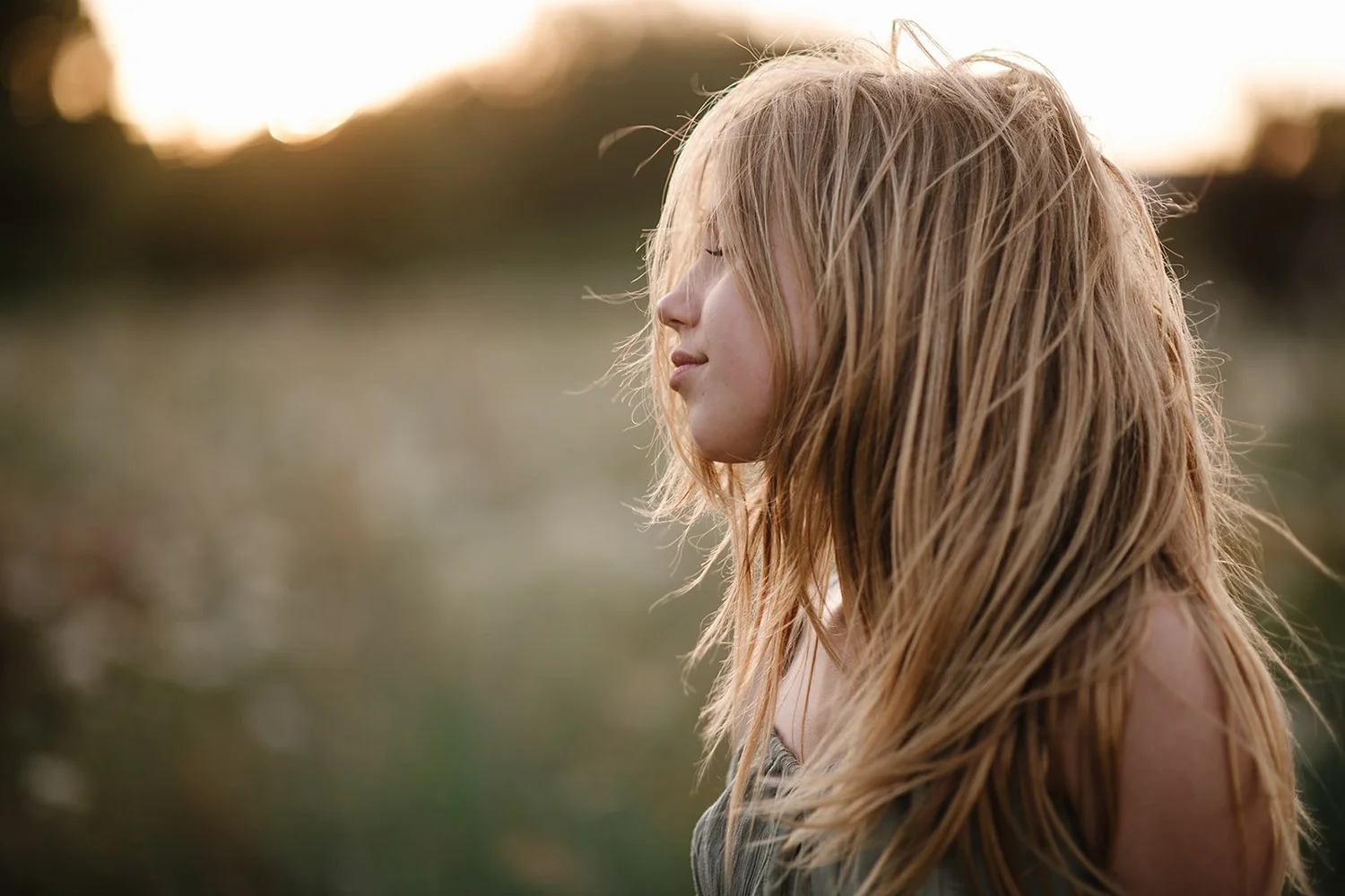 A girl in profile with windblown hair in golden evening light