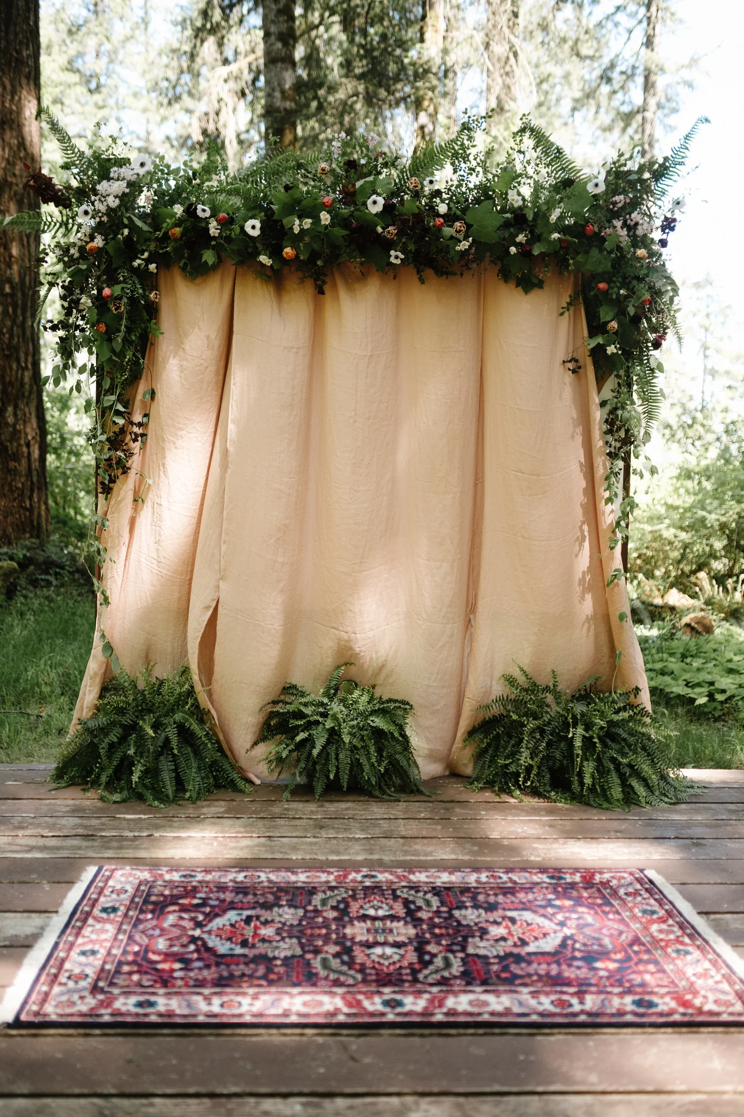 The ceremony backdrop and rug set among the ferns