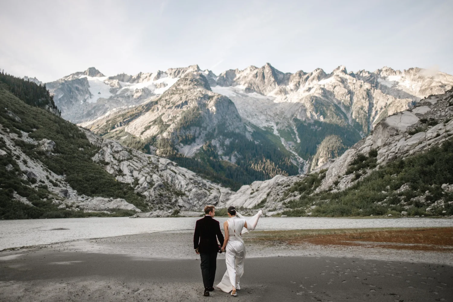 A couple standing on a glacier below snowy peaks