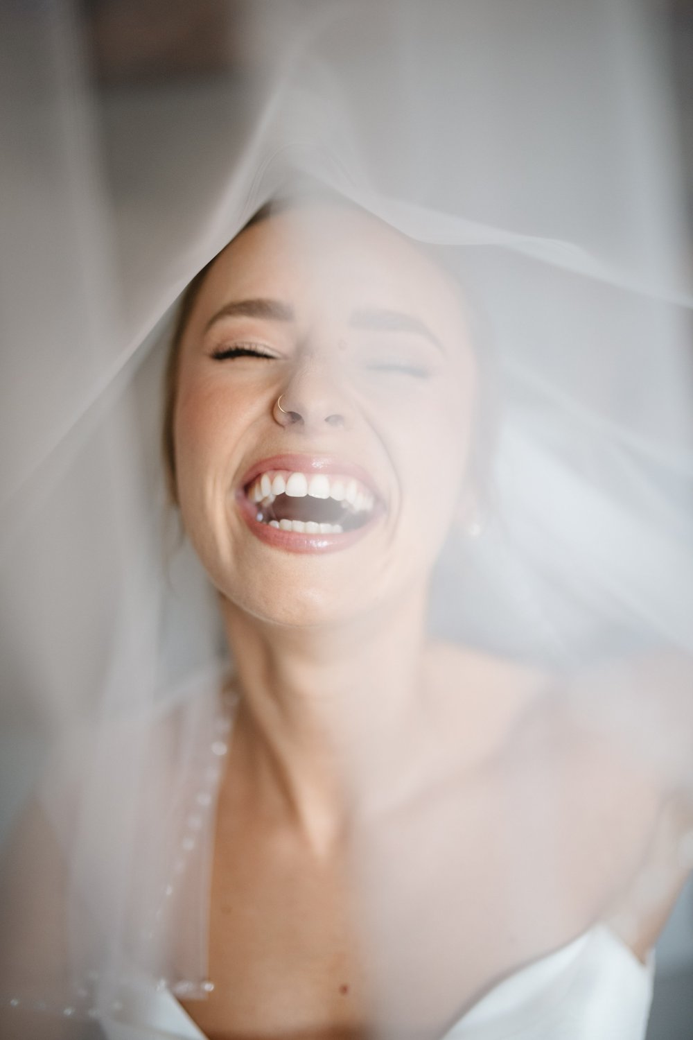 A bride laughing beneath her veil