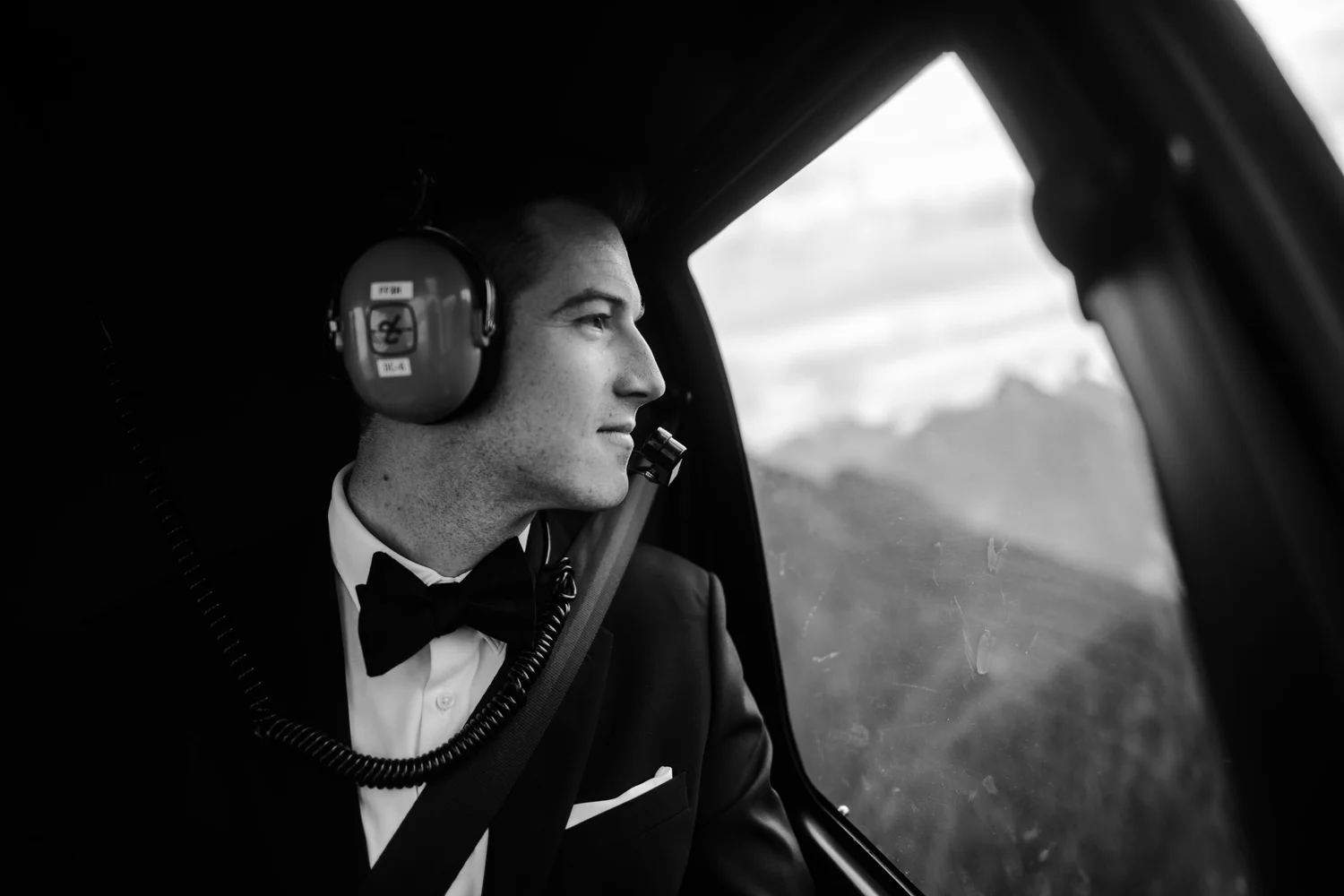 A groom looking out of the helicopter window over the coast mountains