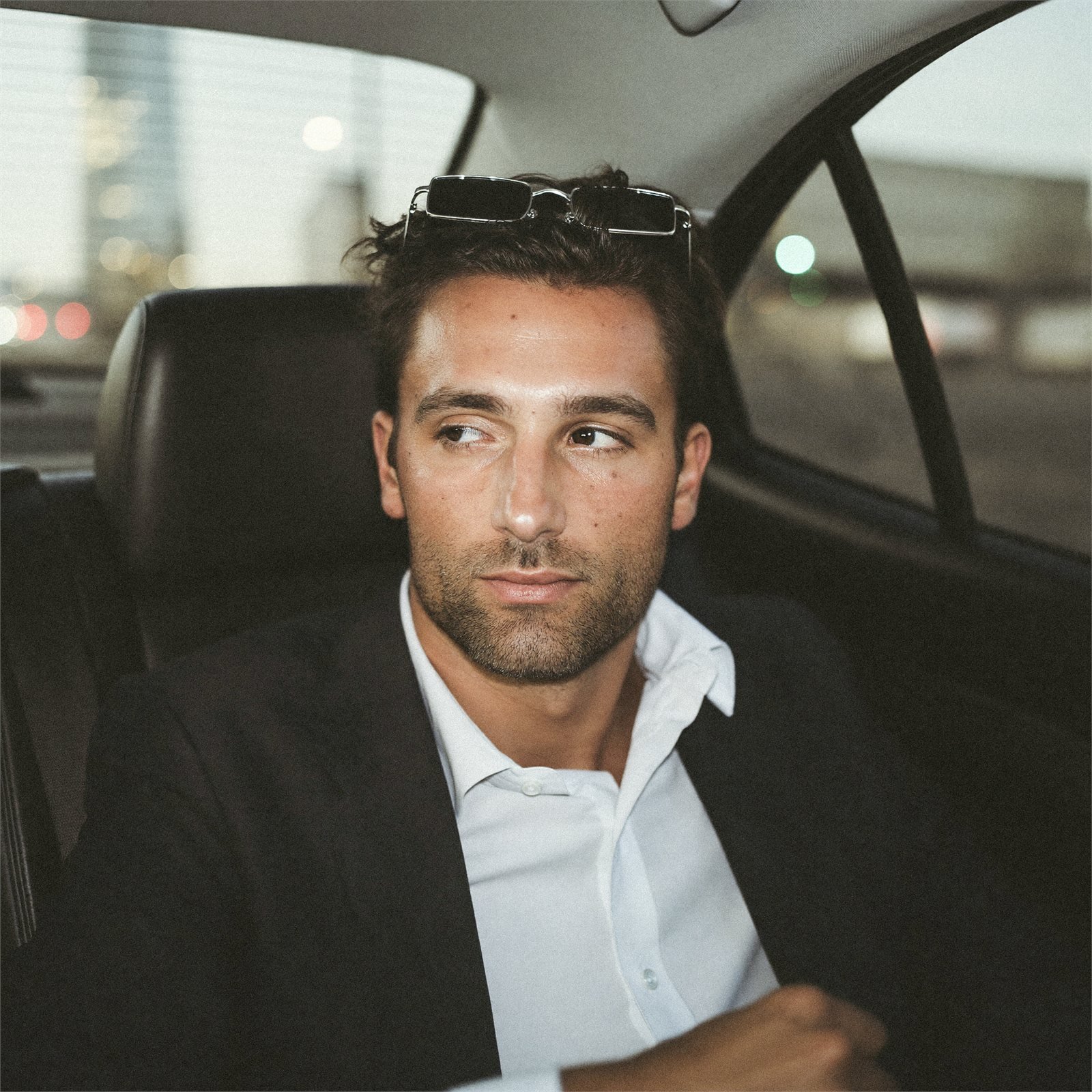 A man in a car, sunglasses pushed up into his hair.