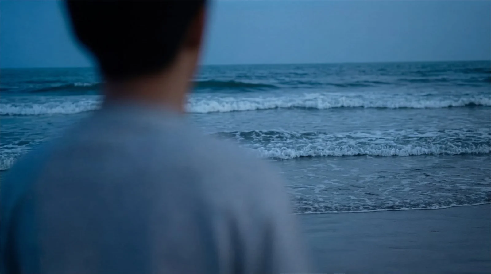 A blurred shoulder in the foreground, the sea in focus beyond.