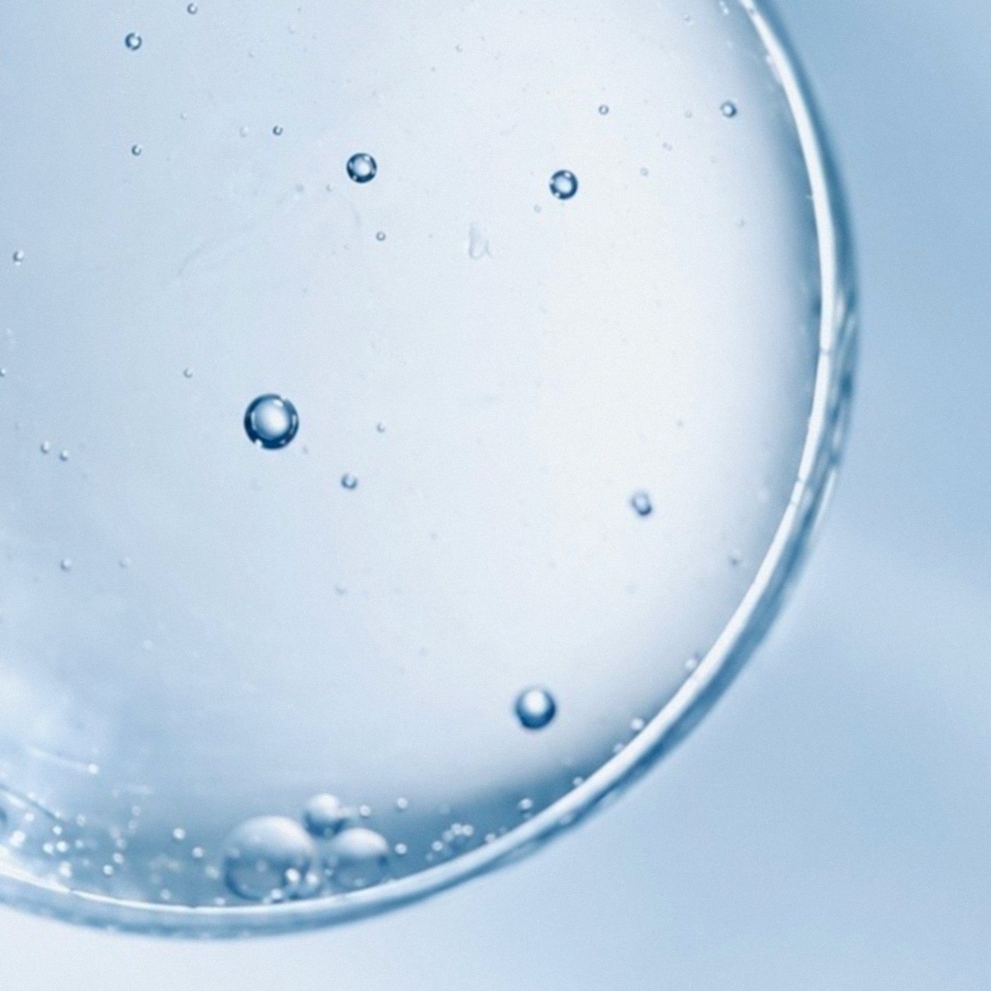 Macro droplets and bubbles floating on a pale blue field.