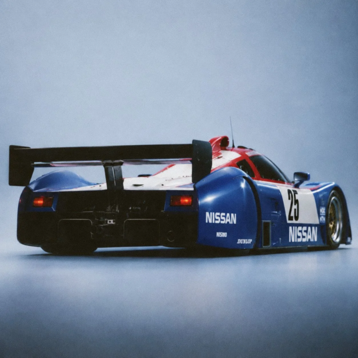 The Nissan R89C seen from behind on a pale blue backdrop.