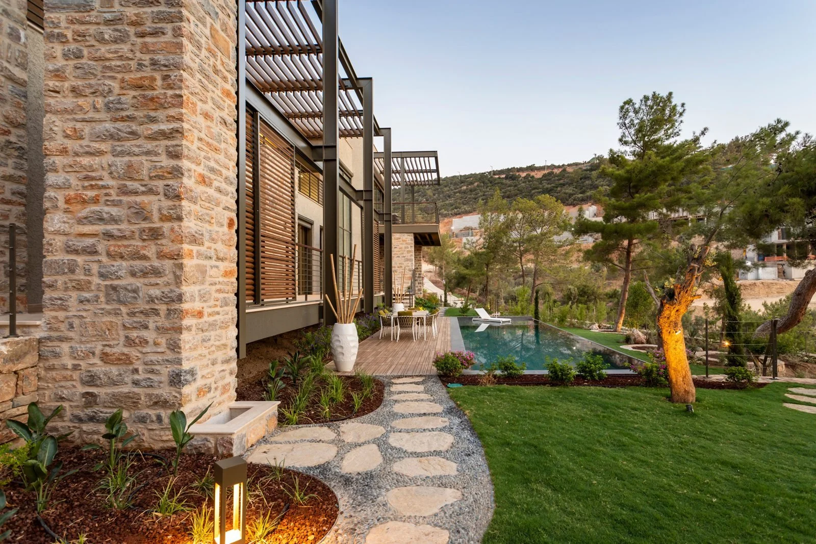 Garden and swimming pool beside a stone-fronted home