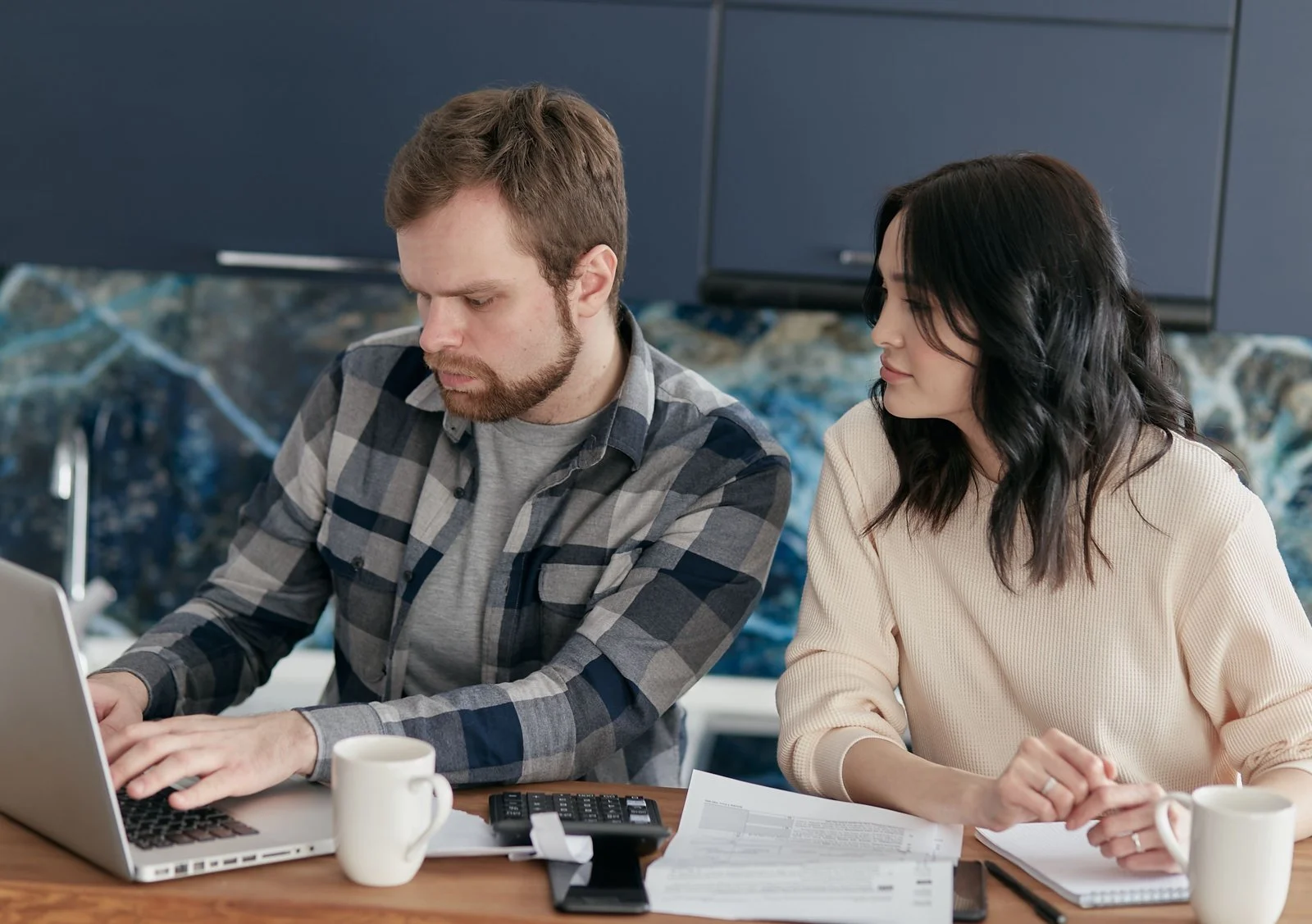 Two people reviewing paperwork together beside a laptop