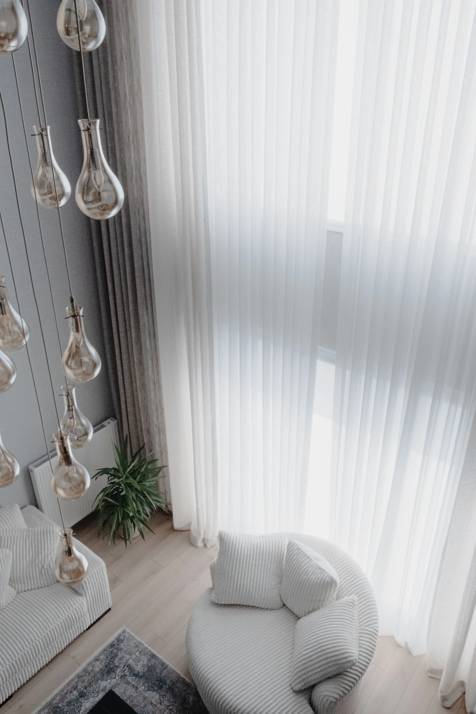 Light-filled sitting area with textured chairs and glass pendant lights