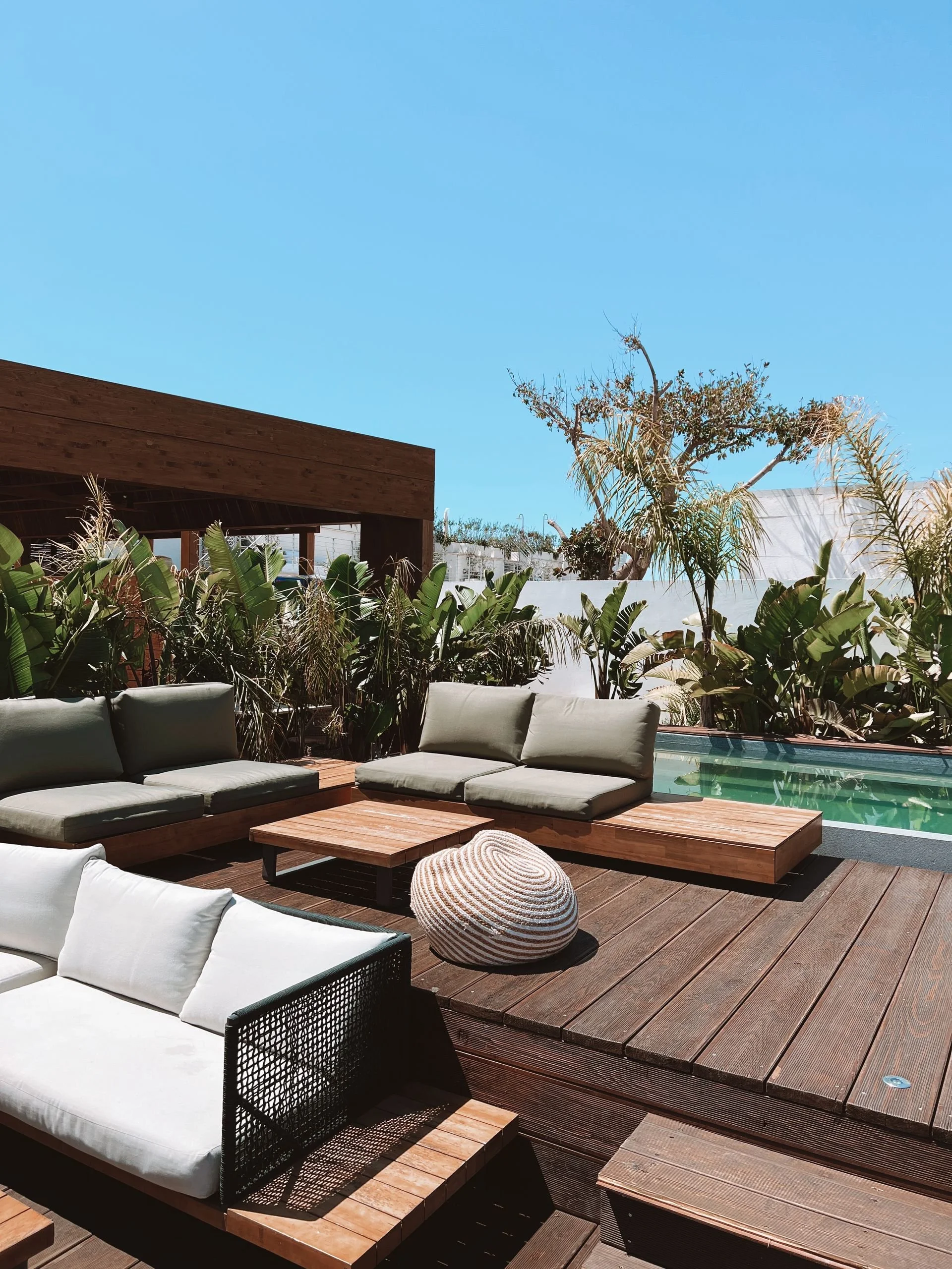 Outdoor terrace with lounge seating, tropical greenery, and a pool